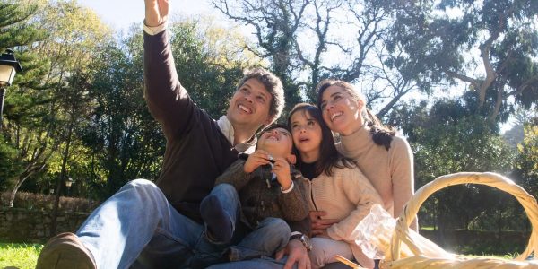 Happy family taking a selfie during a sunny picnic in a park.