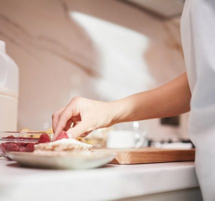 A close-up of a person preparing a raspberry dish on a kitchen counter.