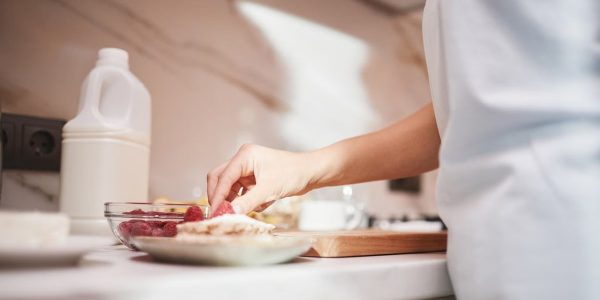 A close-up of a person preparing a raspberry dish on a kitchen counter.